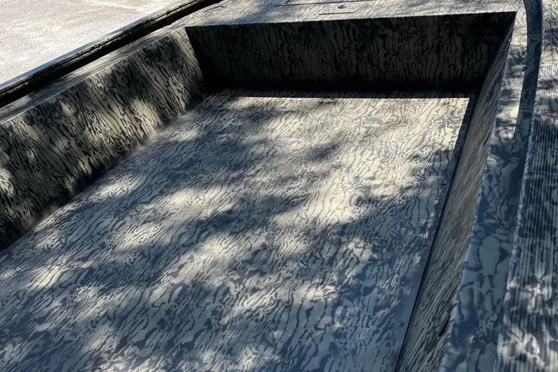 Slide: The Image of 2026 Tracker Grizzly 1648 Utility boat interior with camouflage pattern and sunlight shadows. - 6