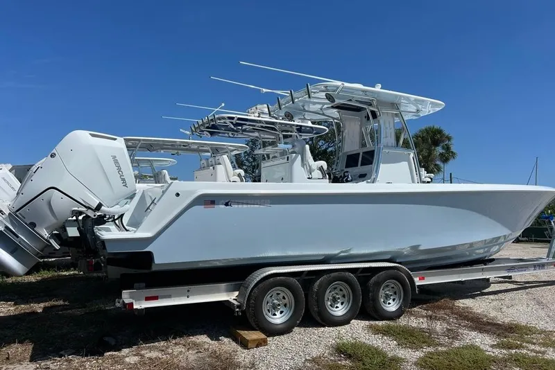 Slide: The Image of 2026 Contender 32 ST boat on trailer with Mercury engines, under clear blue sky. - 2
