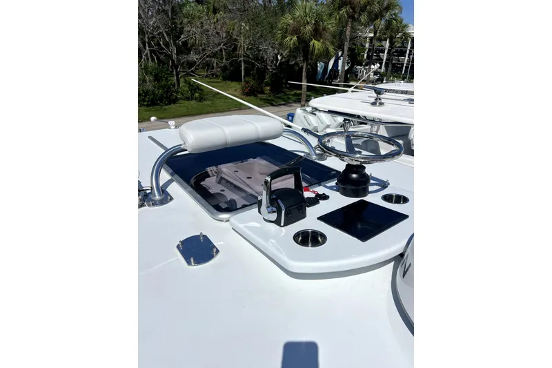 Slide: The Image of 2026 Contender 32 ST boat helm with steering wheel and controls, surrounded by lush greenery. - 8