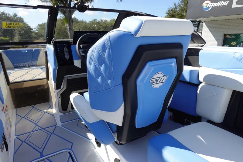 Slide: The Image of 2025 Malibu M230 boat interior with blue and white seating, modern dashboard, and sleek design. - 12