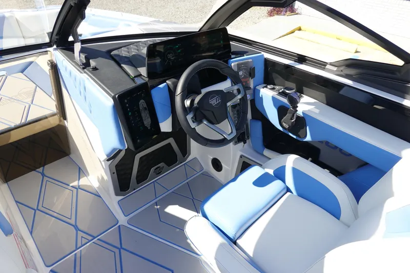 Slide: The Image of 2025 Malibu M230 boat interior with modern dashboard and blue-white seating. - 13