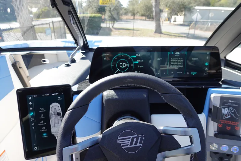 Slide: The Image of 2025 Malibu M230 boat dashboard with digital displays and steering wheel. - 14