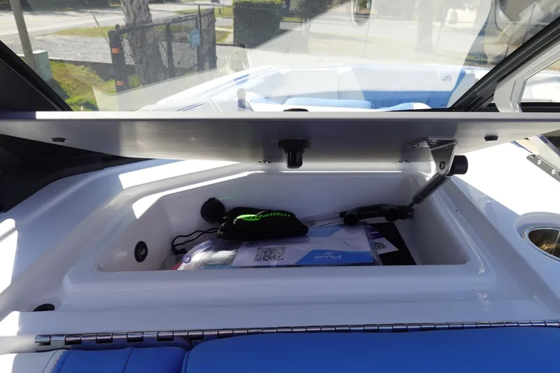 Slide: The Image of 2025 Malibu M230 boat storage compartment with documents and accessories. - 21