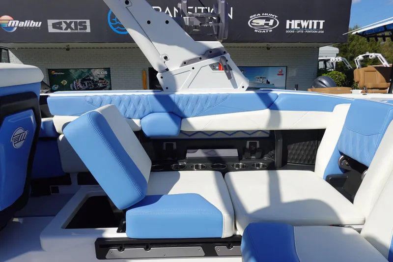 Slide: The Image of 2025 Malibu M230 boat interior with blue and white seating, cup holders, and modern design. - 28