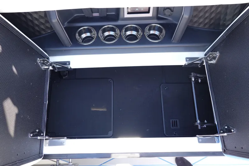 Slide: The Image of 2025 Malibu M230 storage compartment with cup holders and open doors. - 30