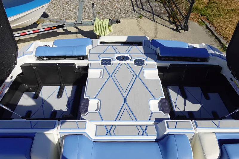 Slide: The Image of 2025 Malibu M230 boat interior with blue and gray seating and storage compartments. - 43