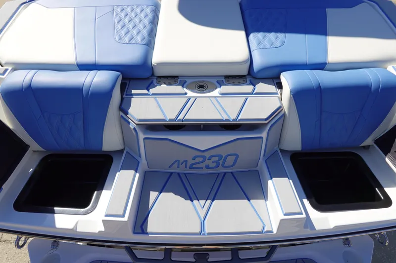 Slide: The Image of 2025 Malibu M230 boat interior with blue and white seating and storage compartments. - 47
