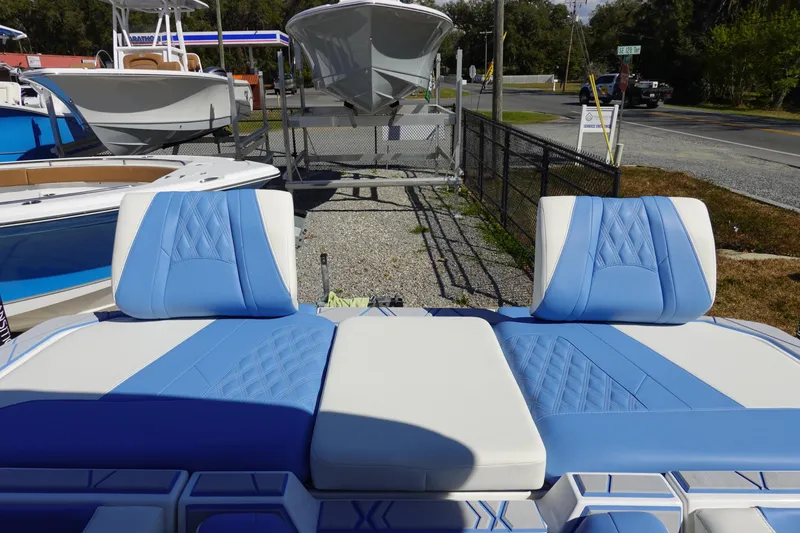 Slide: The Image of 2025 Malibu M230 boat with blue and white seating, displayed outdoors. - 9