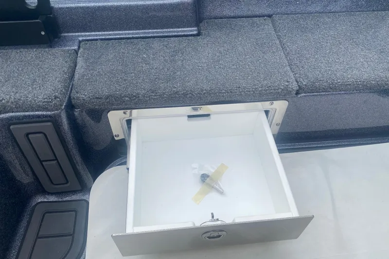 Slide: The Image of Open storage compartment in 2026 Phoenix 21 XE boat, featuring a key inside. - 17