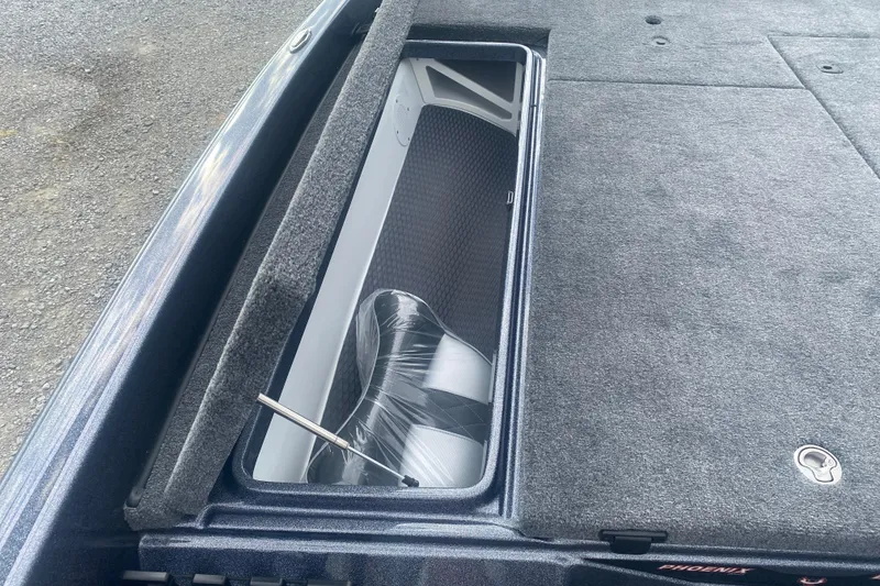 Slide: The Image of Open storage compartment in 2026 Phoenix 21 XE boat, featuring carpeted interior and hydraulic lift. - 23