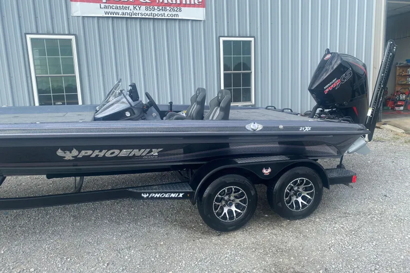 Slide: The Image of 2026 Phoenix 21 XE boat with trailer, parked outside a marine shop. - 5