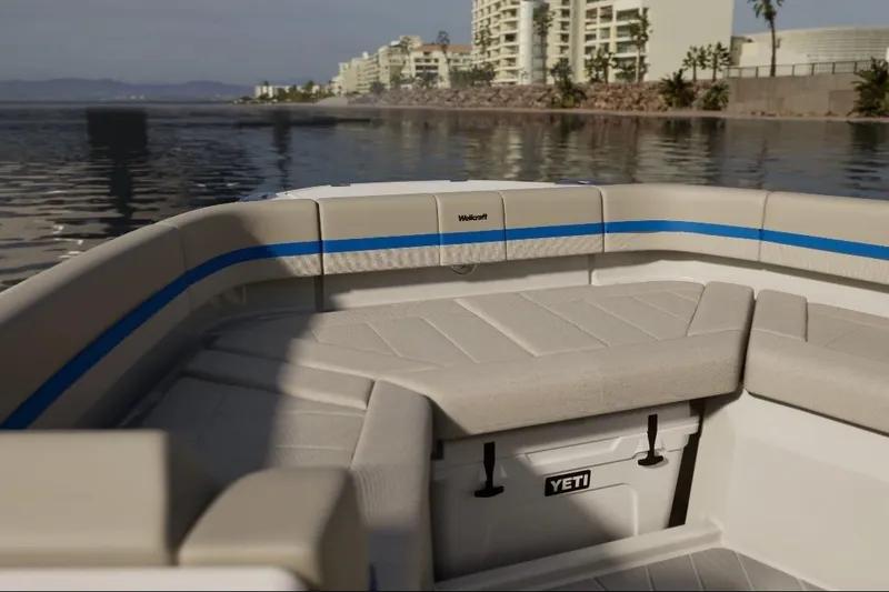 Slide: The Image of 2026 Wellcraft 28 Explorer boat interior with seating and Yeti cooler, near waterfront buildings. - 9