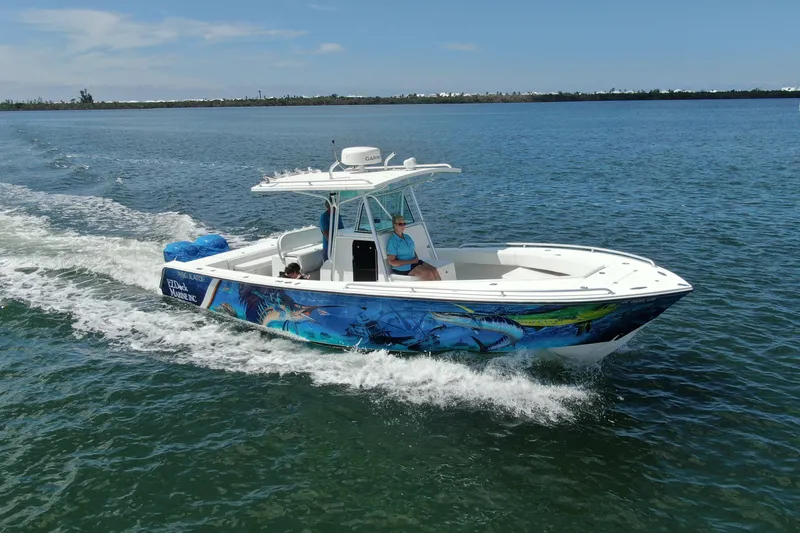 The Image of 2001 Regulator 32 Center Console boat cruising on open water with vibrant marine graphics. - 0