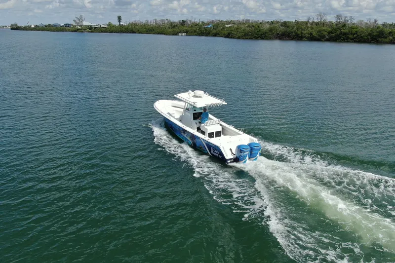 Slide: The Image of 2001 Regulator 32 Center Console boat cruising on a calm lake with lush shoreline. - 13