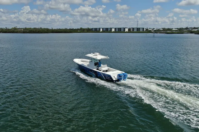Slide: The Image of 2001 Regulator 32 Center Console boat cruising on a calm lake under a cloudy sky. - 19