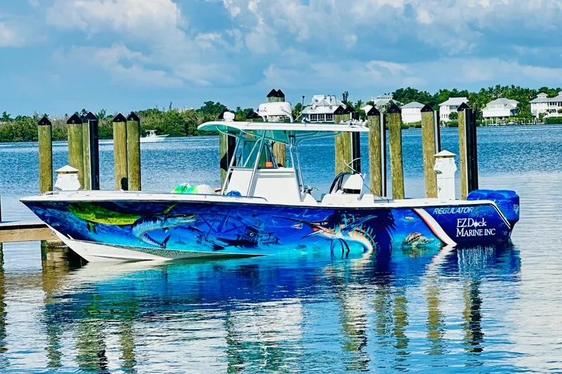 Slide: The Image of 2001 Regulator 32 Center Console boat with vibrant marine-themed artwork docked by the water. - 3