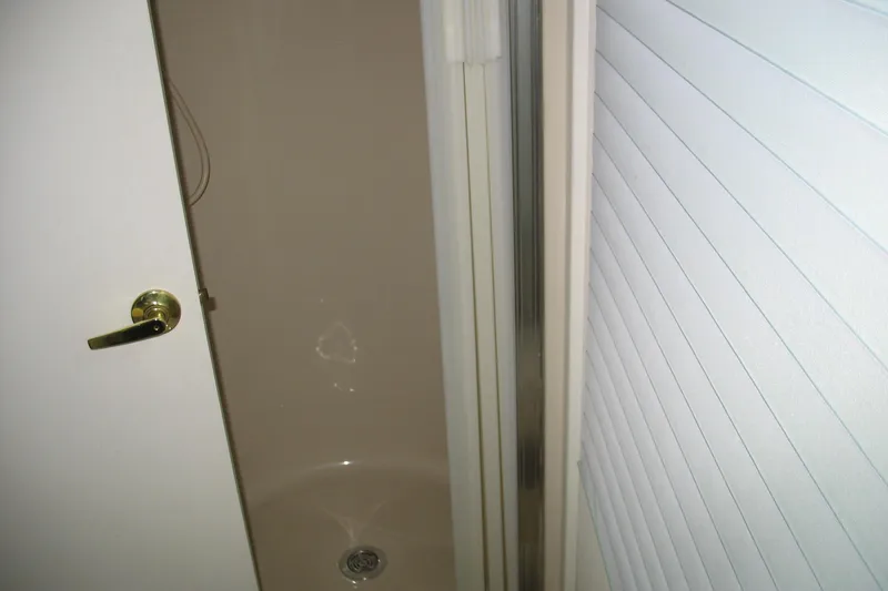 Slide: The Image of Shower area inside a 1993 Skipper Liner houseboat, featuring a white door and handle. - 11