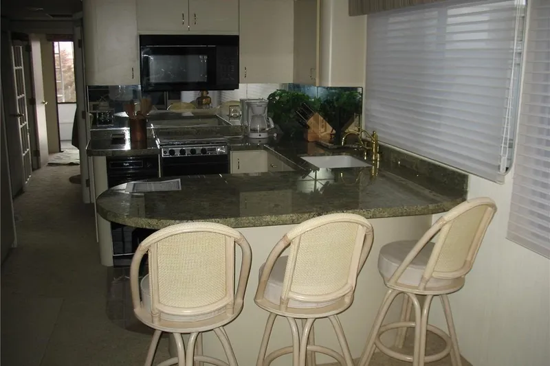 Slide: The Image of 1993 Skipper Liner houseboat kitchen with granite countertops and bar stools. - 24