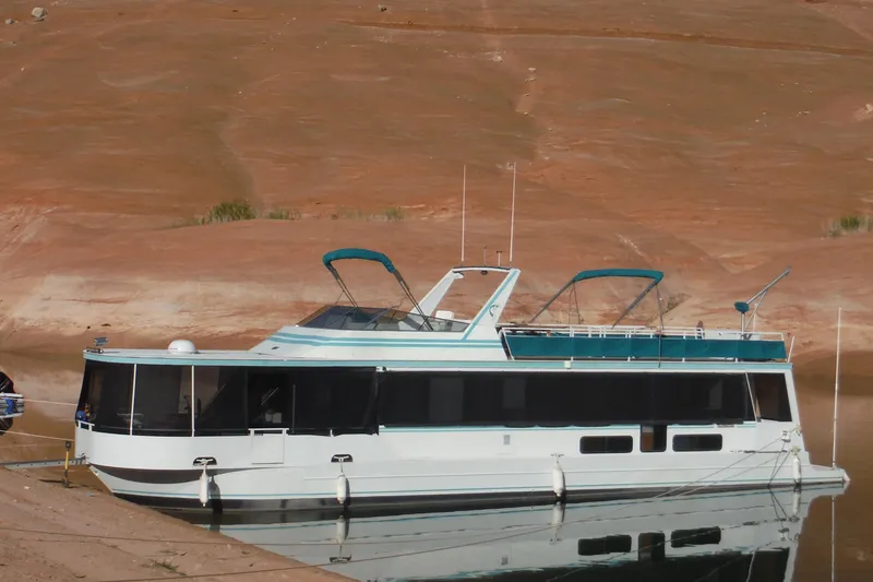 Slide: The Image of 1993 Skipper Liner houseboat docked on a calm lake with desert backdrop. - 3