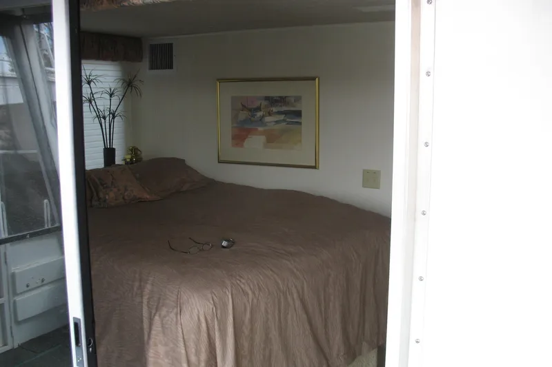 Slide: The Image of Cozy bedroom in 1993 Skipper Liner houseboat with framed artwork and brown bedding. - 37