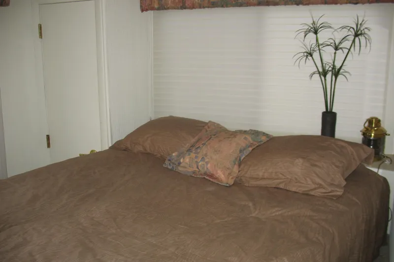 Slide: The Image of Cozy bedroom interior on 1993 Skipper Liner houseboat with brown bedding and decorative plant. - 41