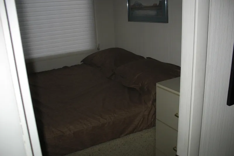 Slide: The Image of Cozy bedroom interior on 1993 Skipper Liner houseboat with brown bedding and dresser. - 44