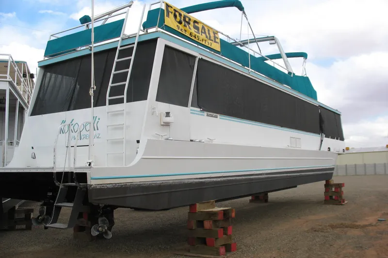 Slide: The Image of 1993 Skipper Liner houseboat for sale, elevated on blocks, with teal accents and "For Sale" sign. - 5