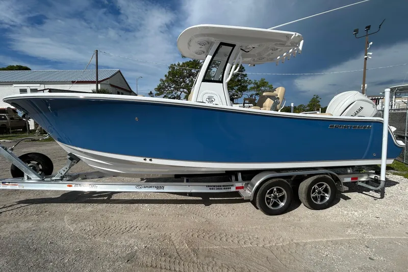 The Image of 2026 Sportsman Open 232 Center Console boat on trailer, blue hull, outdoor setting. - 1