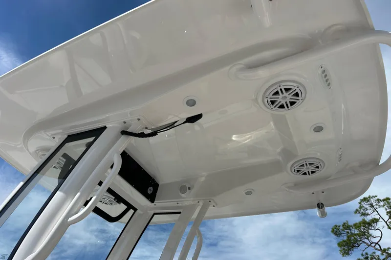 Slide: The Image of 2026 Sportsman Open 232 Center Console boat's T-top with speakers and lights against blue sky. - 14