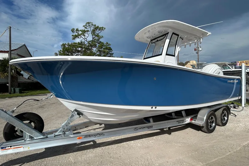 Slide: The Image of 2026 Sportsman Open 232 Center Console boat on trailer, blue hull, parked outdoors. - 4