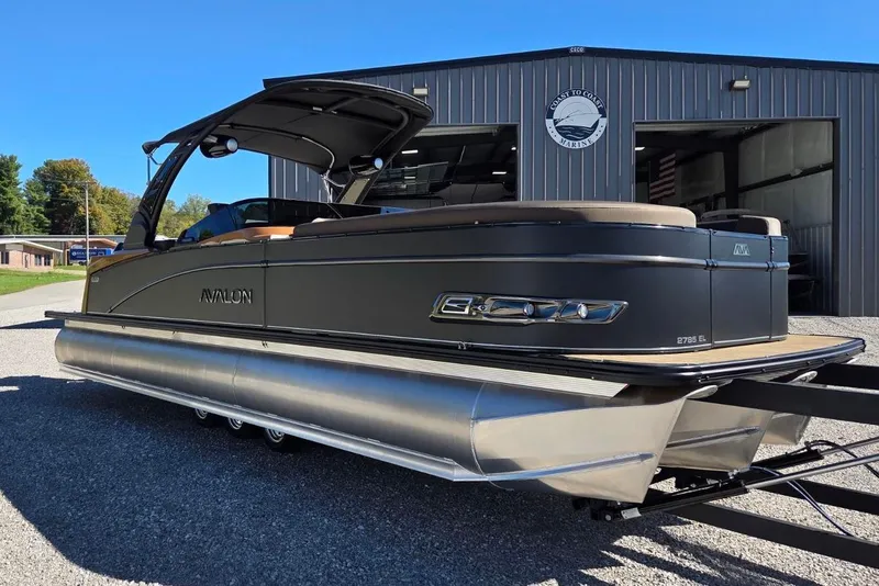 Slide: The Image of 2026 Avalon Platinum Catalina 2785 Elite Windshield pontoon boat parked outside marina. - 3