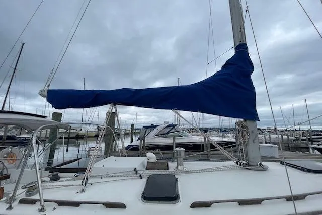 Slide: The Image of 1978 Hinterhoeller Niagara 35 Classic sailboat docked, featuring a blue sail cover. - 12