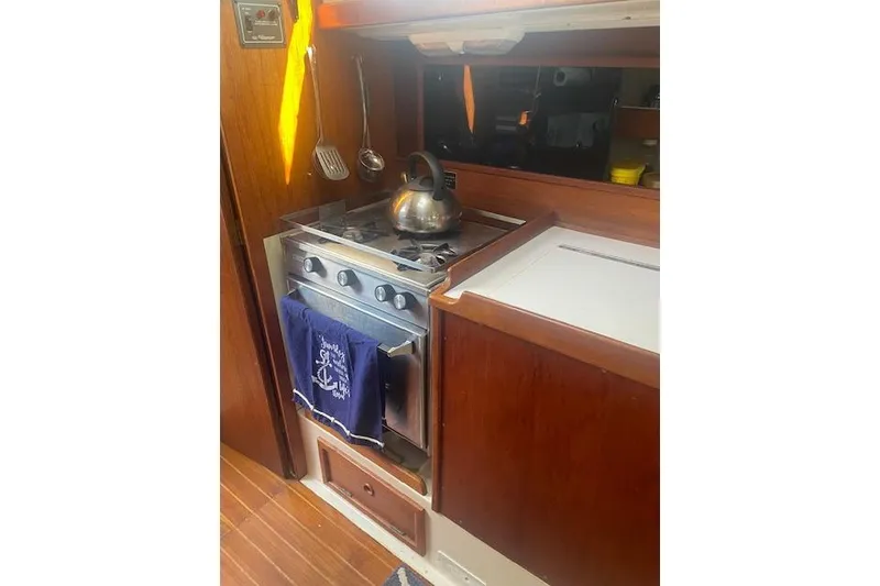 Slide: The Image of 1978 Hinterhoeller Niagara 35 Classic yacht kitchen with stove, kettle, and hanging utensils. - 31
