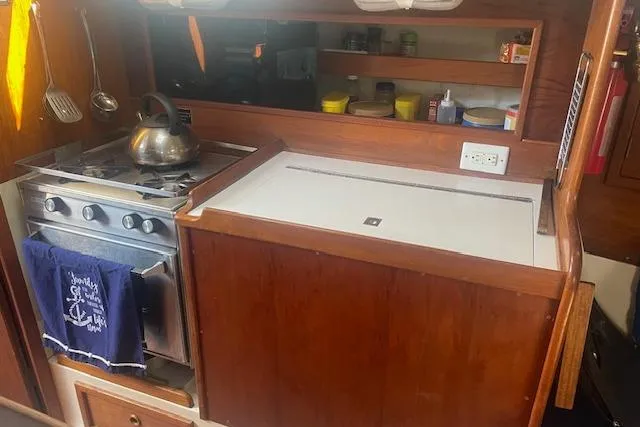 Slide: The Image of 1978 Hinterhoeller Niagara 35 Classic yacht kitchen with stove, kettle, and wooden cabinetry. - 32