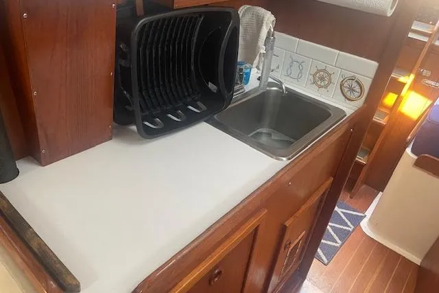 Slide: The Image of 1978 Hinterhoeller Niagara 35 Classic yacht kitchen with sink, dish rack, and nautical-themed tiles. - 33