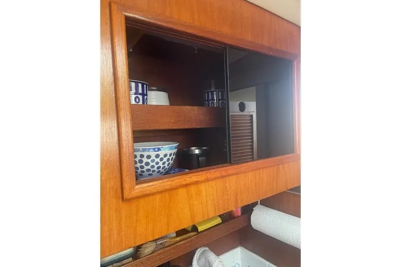 Slide: The Image of Wooden cabinet with blue-patterned dishes on a 1978 Hinterhoeller Niagara 35 Classic sailboat. - 36