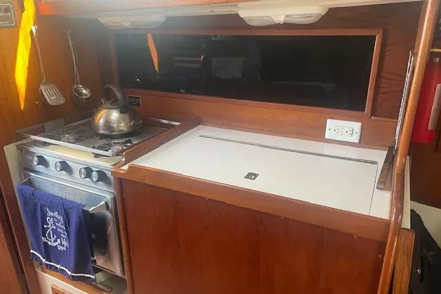 Slide: The Image of 1978 Hinterhoeller Niagara 35 Classic yacht kitchen with stove, kettle, and wooden cabinetry. - 37