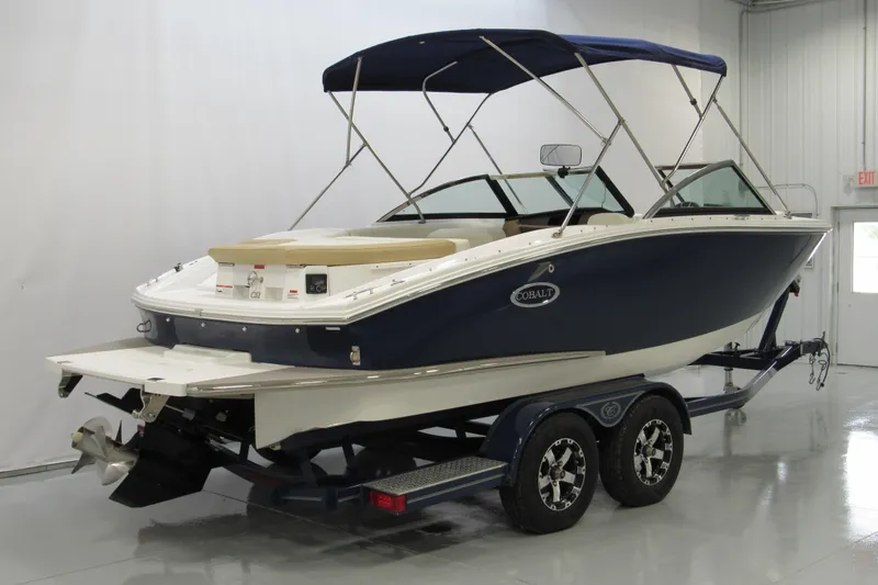 Slide: The Image of 2017 Cobalt CS1 boat on trailer in indoor showroom, featuring blue and white design. - 2