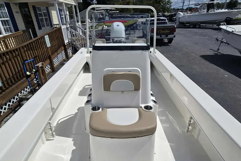 Slide: The Image of 2026 Sundance B22CCR boat interior with seating and console, parked outdoors. - 10