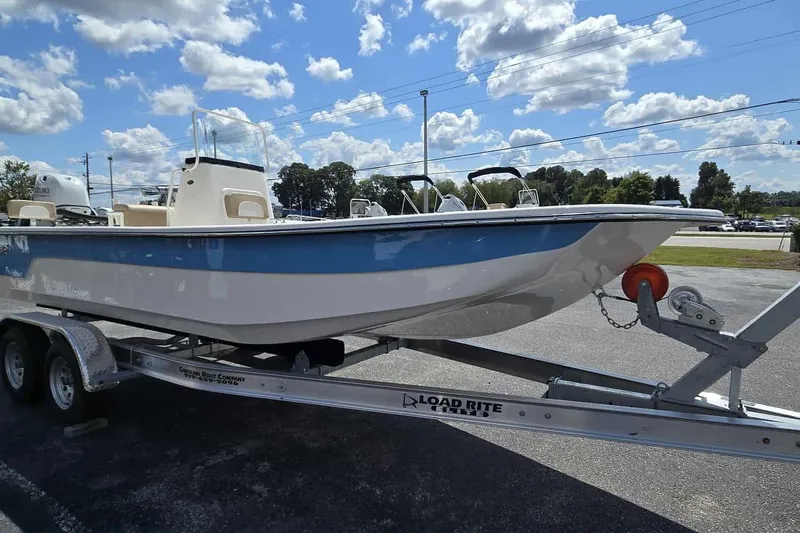 Slide: The Image of 2026 Sundance B22CCR boat on trailer under a bright blue sky with clouds. - 2