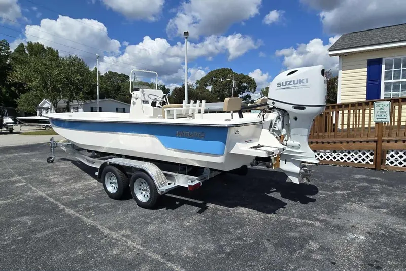 Slide: The Image of 2026 Sundance B22CCR boat with Suzuki engine on trailer, parked outdoors. - 4