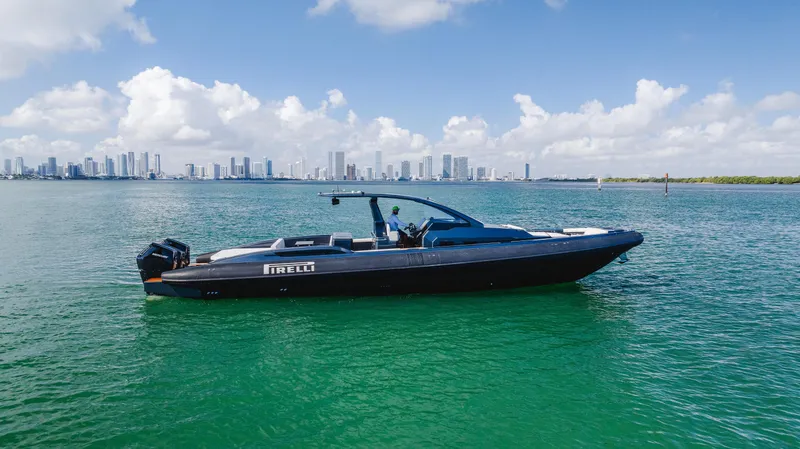 Slide: The Image of 2023 Pirelli Tecnorib 50 boat on calm water with city skyline in background. - 15