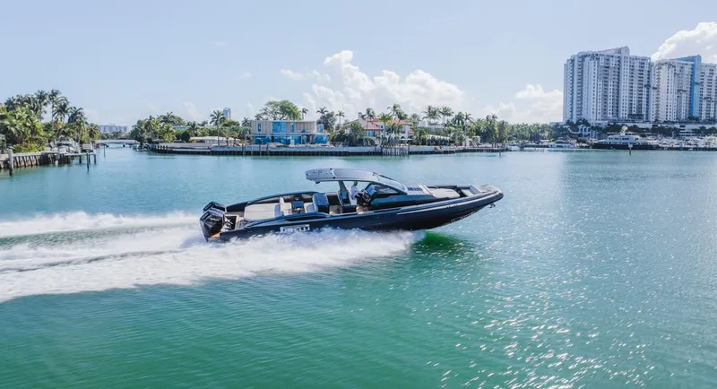 Slide: The Image of 2023 Pirelli Tecnorib 50 speedboat cruising on a sunny waterfront with cityscape background. - 2