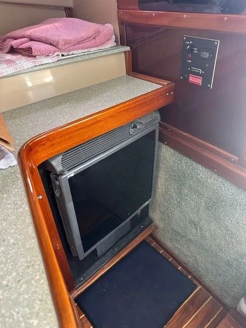 Slide: The Image of Interior of 1987 Shamrock 31 GS boat with compact fridge and control panel. - 21