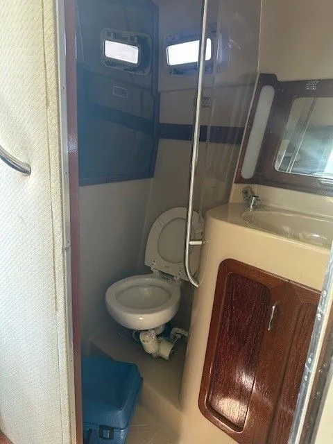 Slide: The Image of 1987 Shamrock 31 GS boat bathroom with toilet, sink, and wooden cabinet. - 23