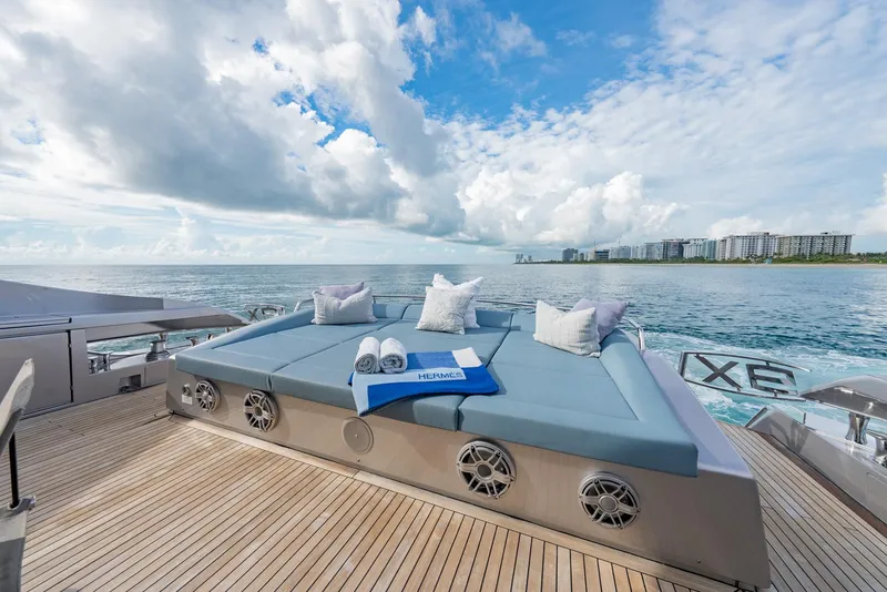 Slide: The Image of Luxurious 2021 Pershing 9X yacht deck with sunbed, ocean view, and coastal skyline. - 12