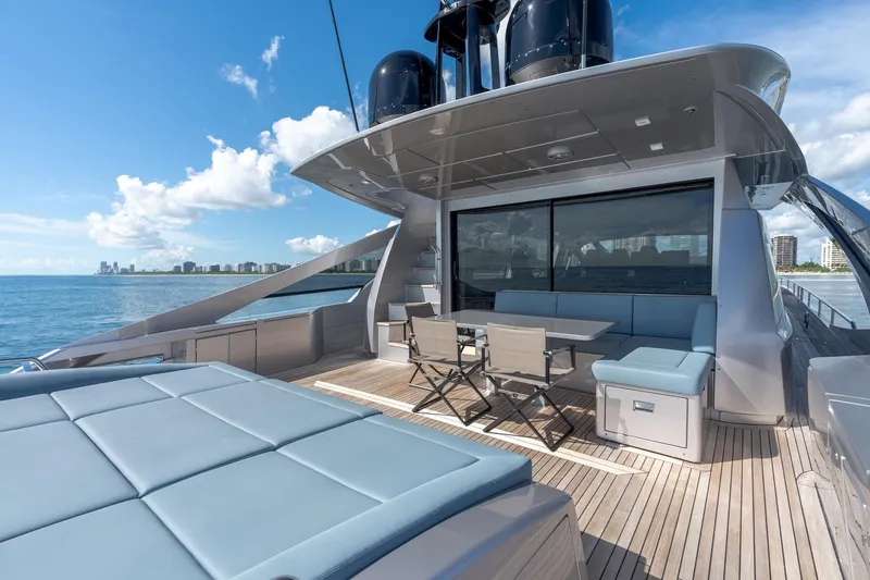 Slide: The Image of Luxurious 2021 Pershing 9X yacht deck with seating, ocean view, and city skyline in the background. - 13