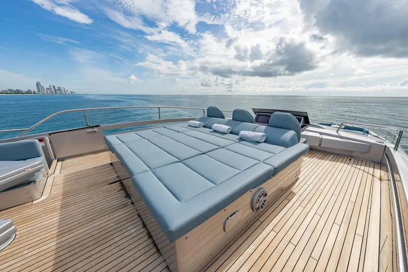 Slide: The Image of Luxurious 2021 Pershing 9X yacht deck with sunbeds, ocean view, and city skyline. - 41
