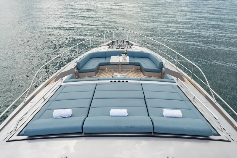 Slide: The Image of Luxury 2021 Pershing 9X yacht deck with sunbeds and seating area on calm water. - 45