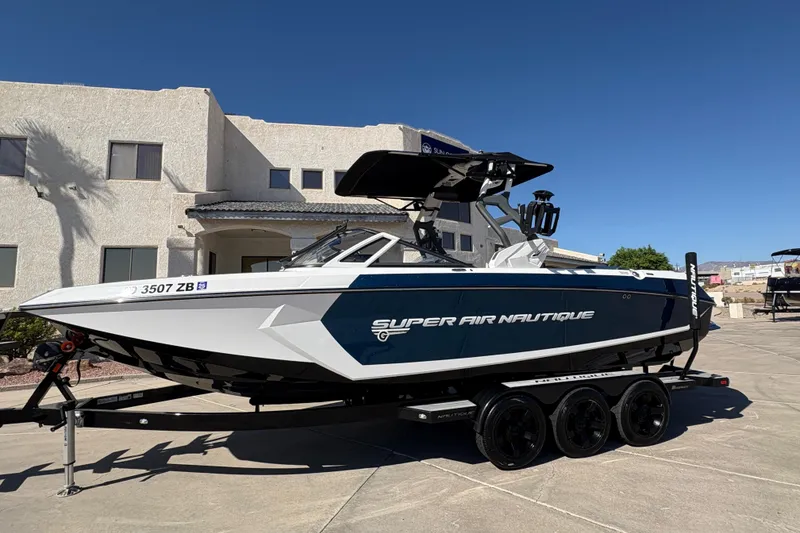 Slide: The Image of 2018 Nautique Super Air Nautique G25 boat on trailer, parked in front of a house. - 2